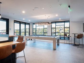 A room with a pool table and chairs.